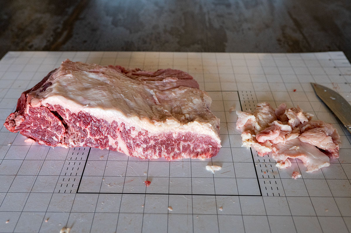 removing fat layer from brisket point to 1/4 inch thickness.