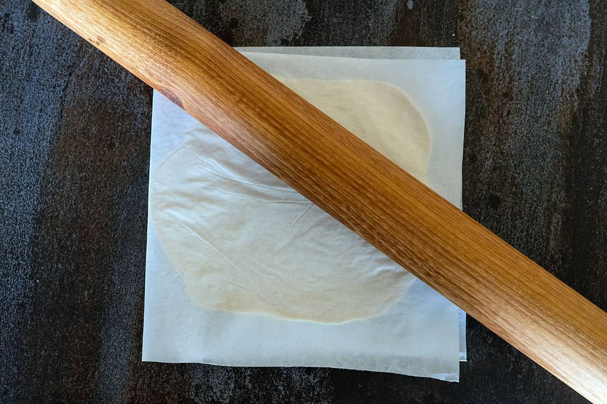 flattening tortilla with rolling pin.