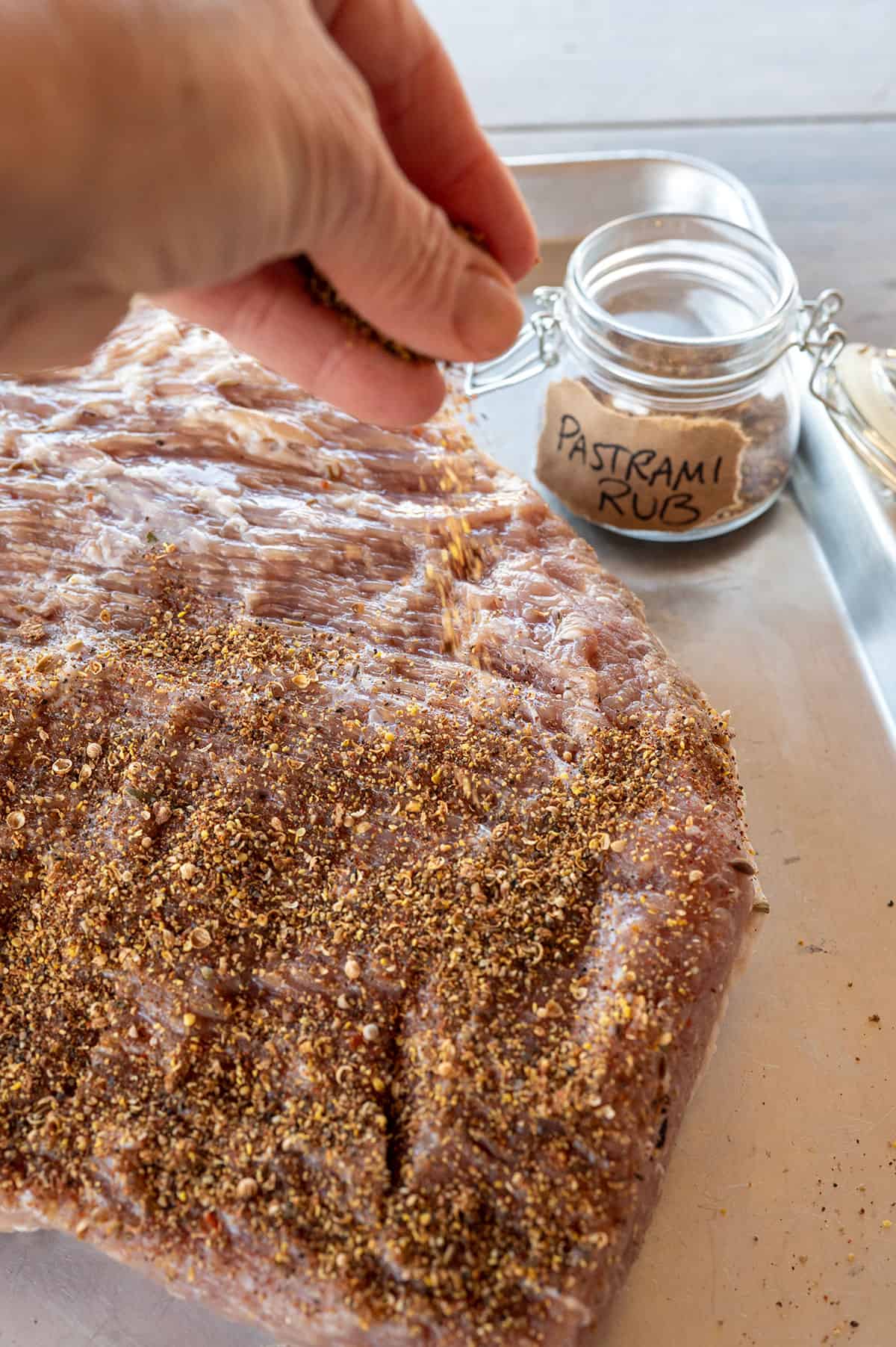 sprinkling pastrami rub on corned beef brisket.