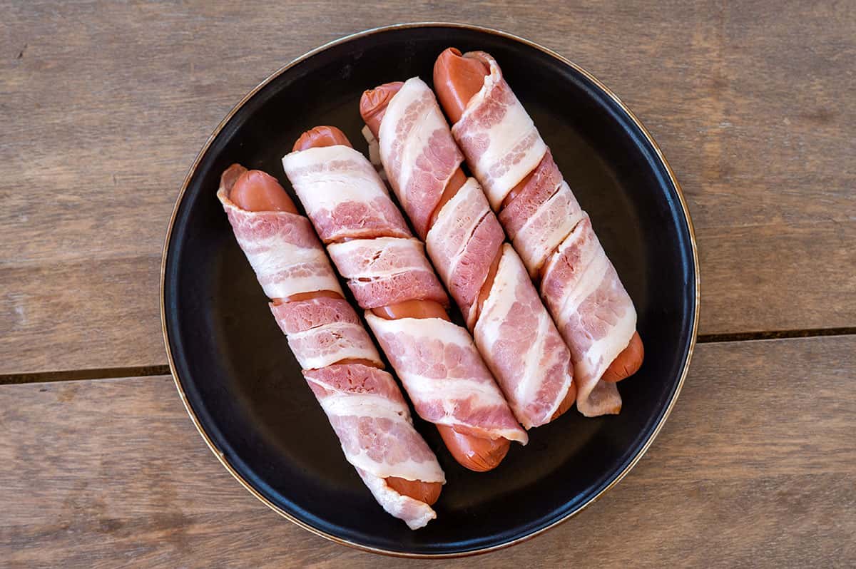 four hot dogs wrapped in bacon.