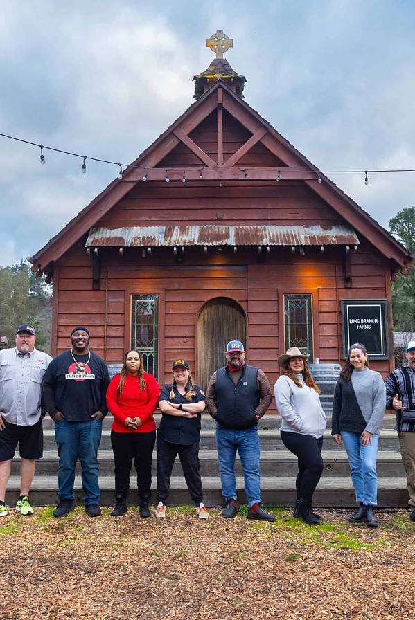 cast of Season 4 of BBQ Brawl in front of a chapel.