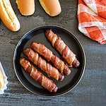 4 bacon-wrapped hot dogs on plate, 1 on bun.