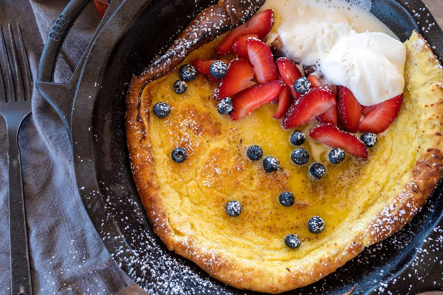 Dutch baby pancake topped with blueberries, strawberries and cream.