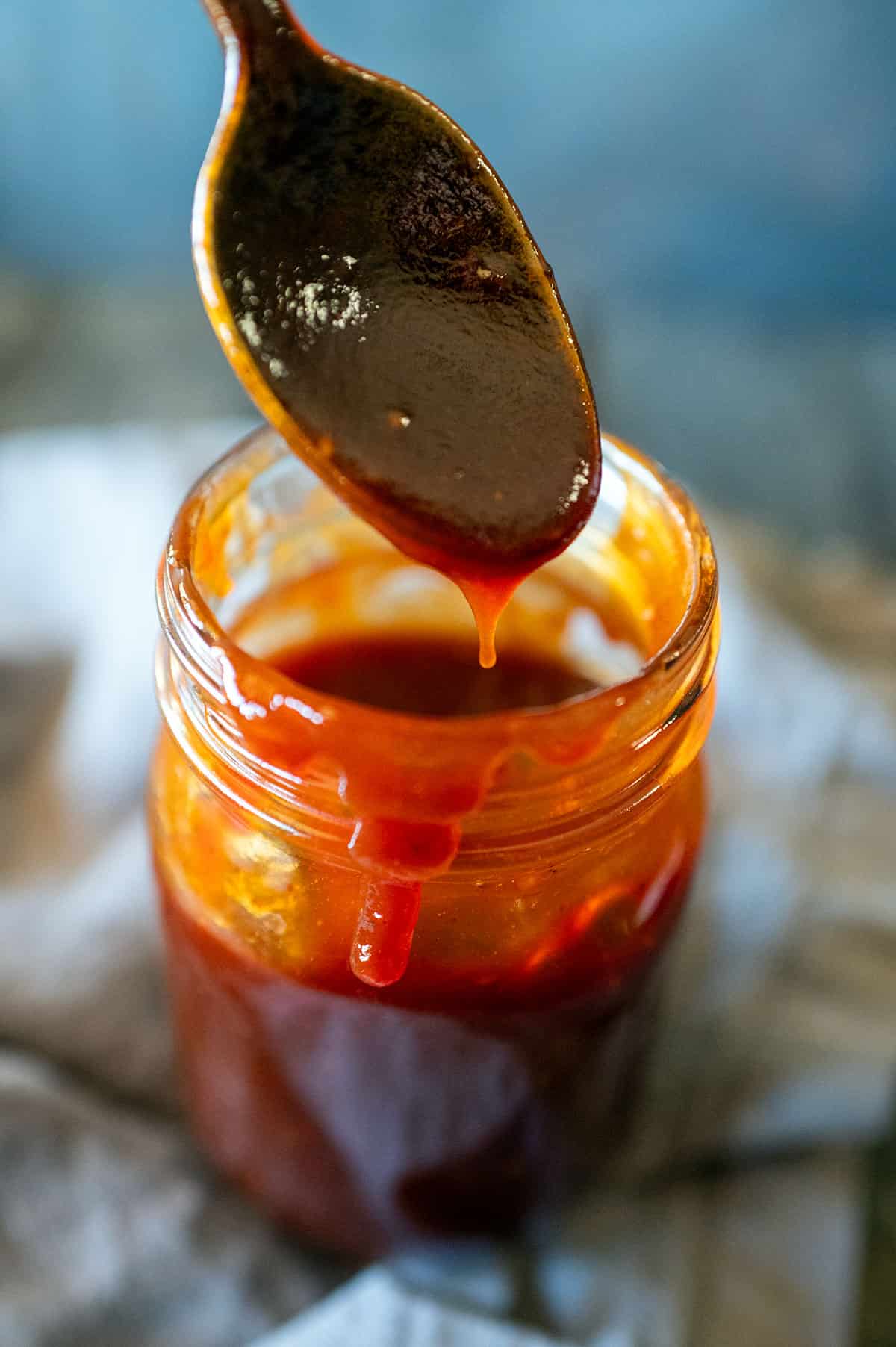 Spoon scooping BBQ sauce out of a jar.