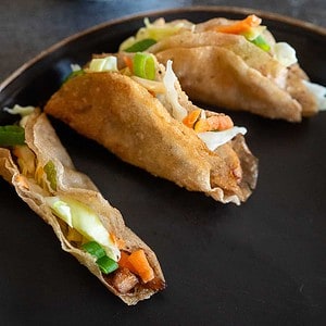 Three chicken lumpia tacos on a plate.