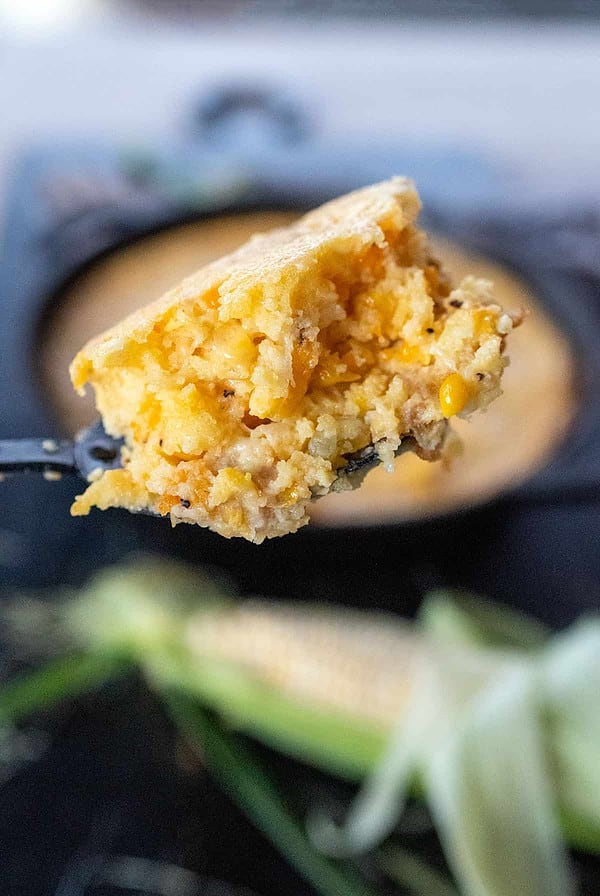 Taking a spoonful of corn pudding casserole.