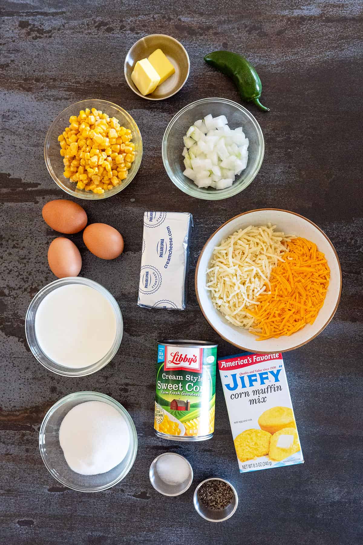 Corn pudding ingredients: butter, cheese, cream cheese, corn, onions, jalapeno, eggs, jiffy cornbread mix, creamed corn, sugar, cream.