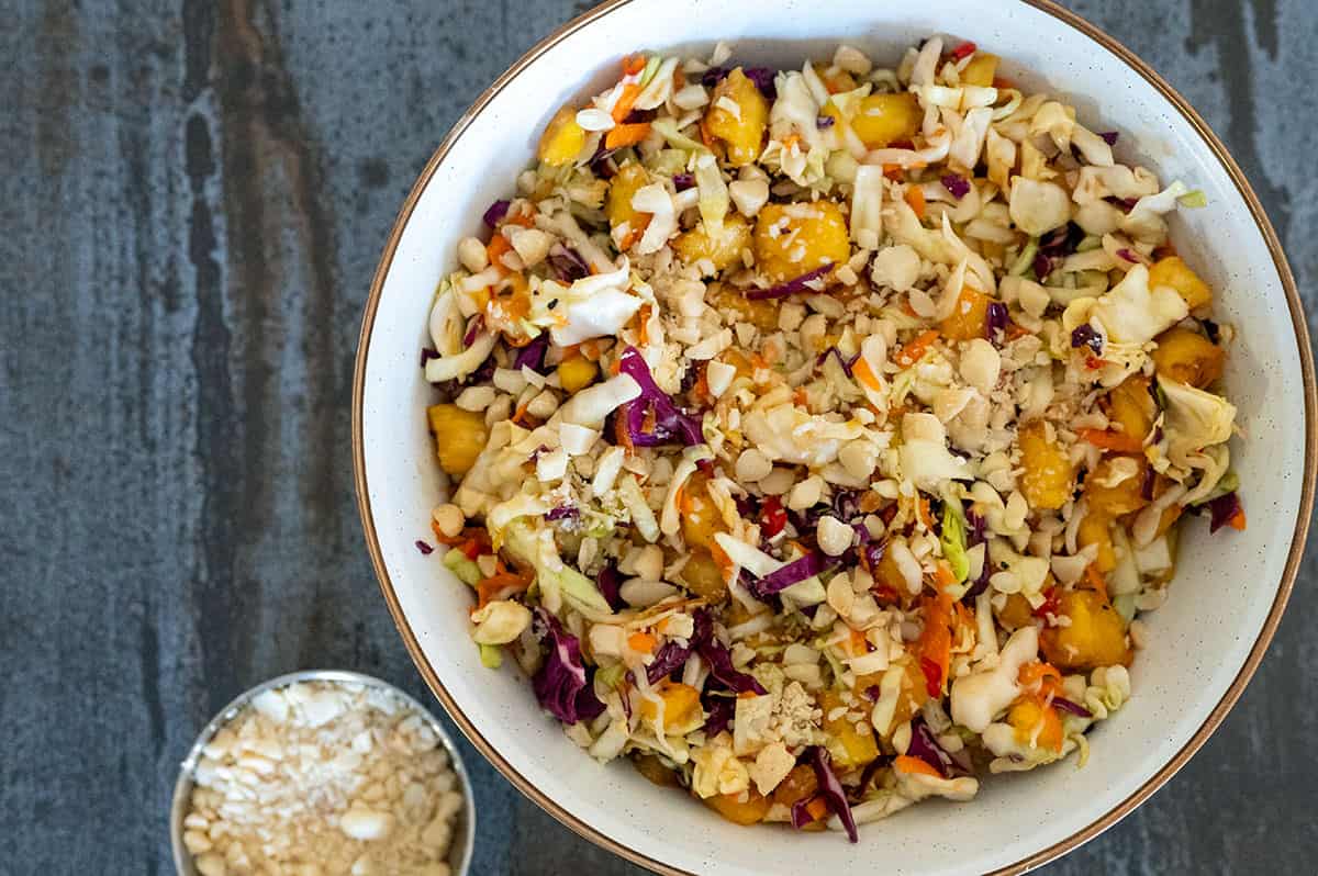 Hawaiian Grilled Pineapple Coleslaw in serving bowl topped with macadamia nuts.