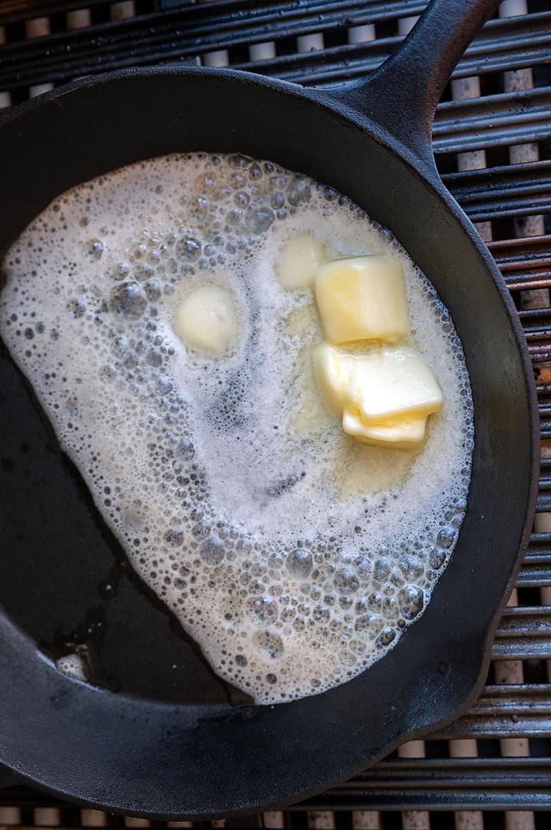 butter melting in cast iron skillet on grill.