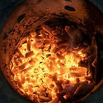 Wood pellets burning in a fire pot of a pellet smoker.