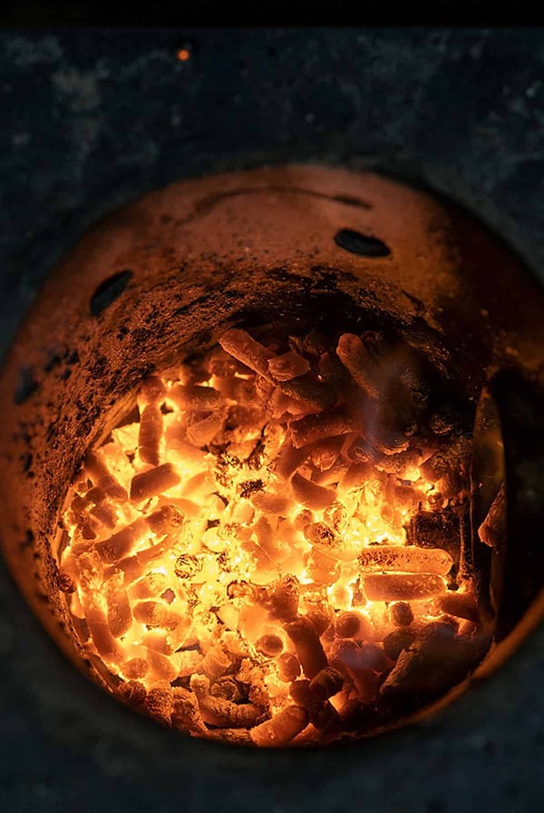 Wood pellets burning in a fire pot of a pellet smoker.