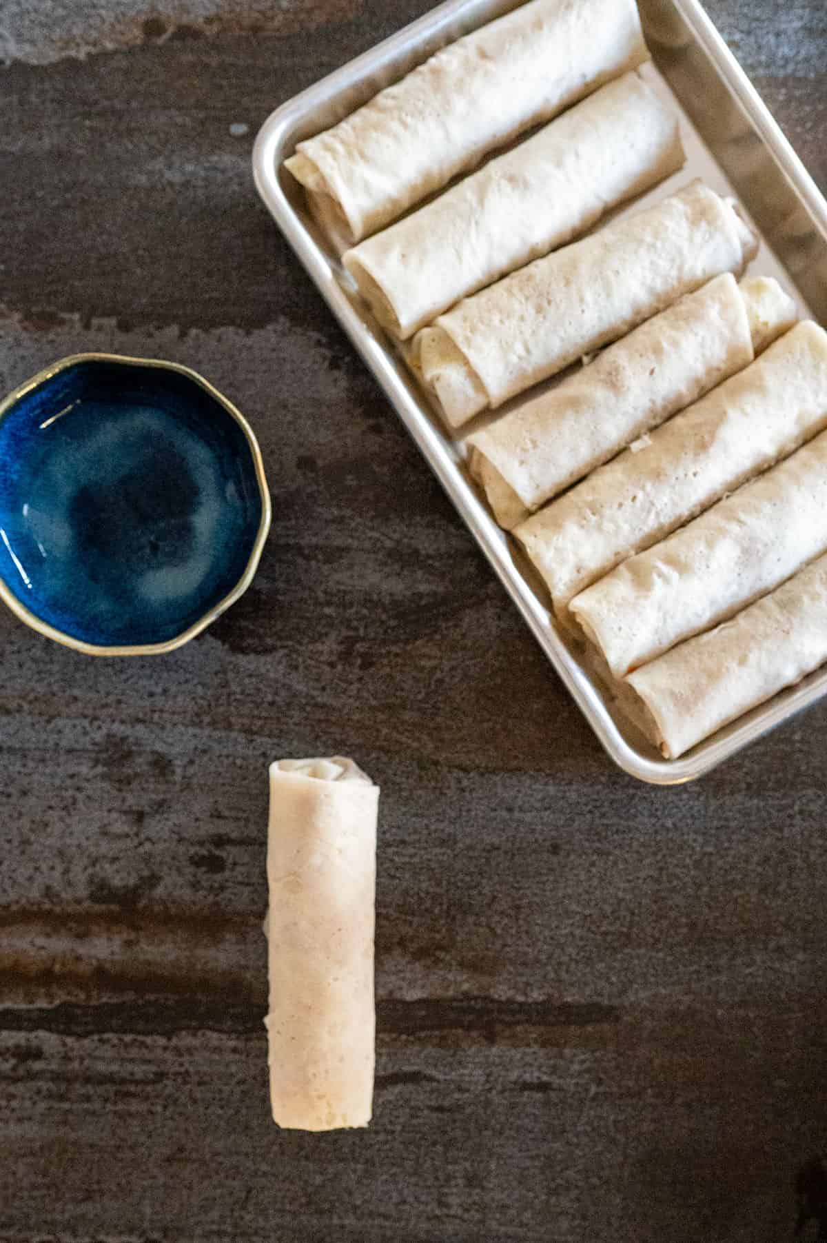 Rolled lumpia on a pan.