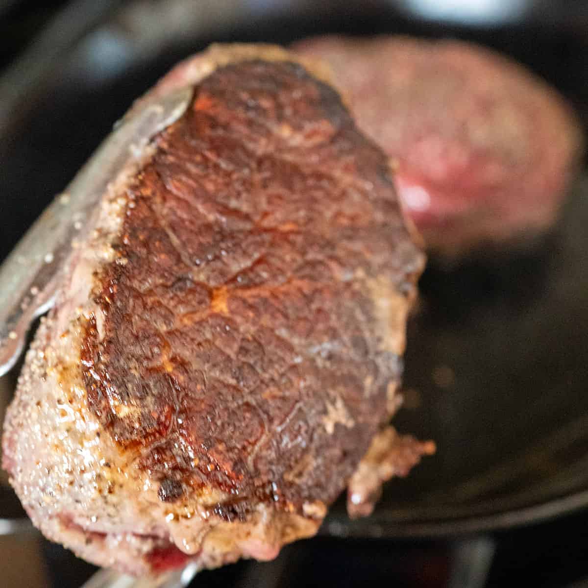 Lifting seared steak to show seared bottom.