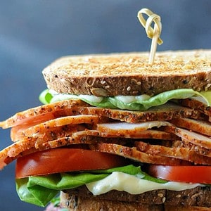 sandwich with sliced pork lunch meat, tomatoes and lettuce.