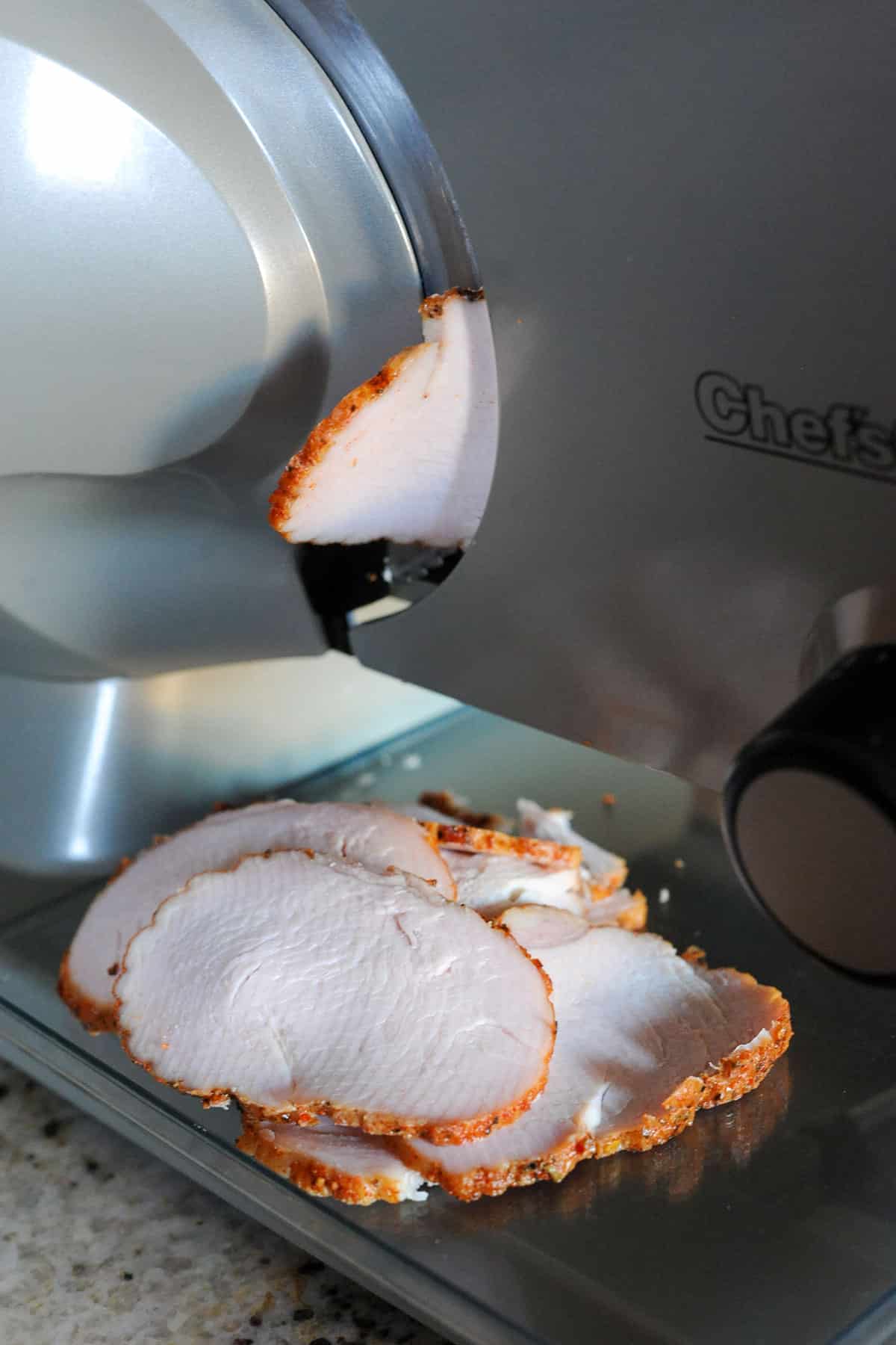 slicing smoked turkey roast with meat slicer.