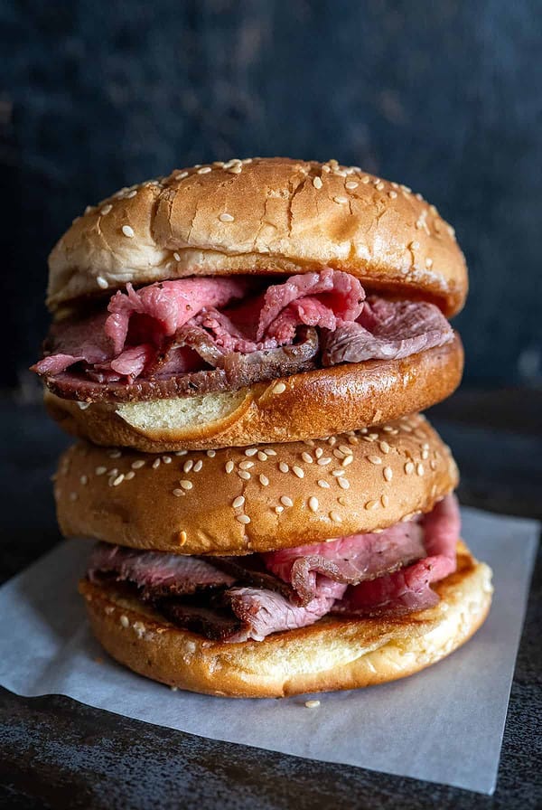 Two roast beef sandwiches stacked on top of each other.