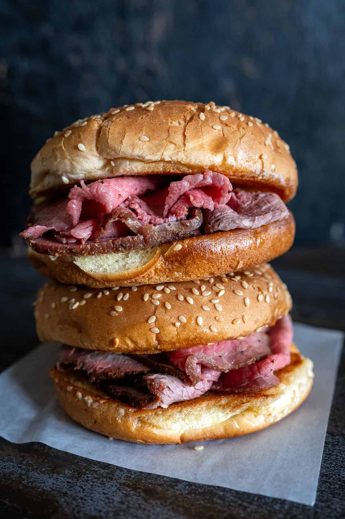 Two roast beef sandwiches stacked on top of each other. 