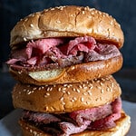 Two roast beef sandwiches stacked on top of each other.