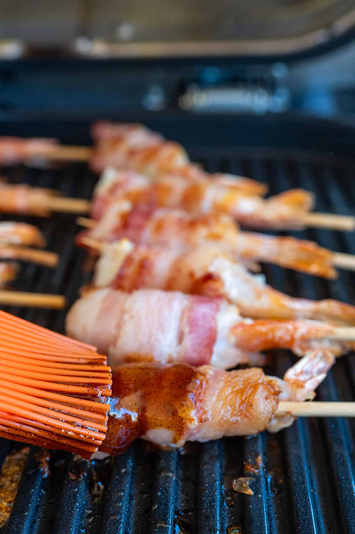 Brushing bacon-wrapped shrimp with glaze.