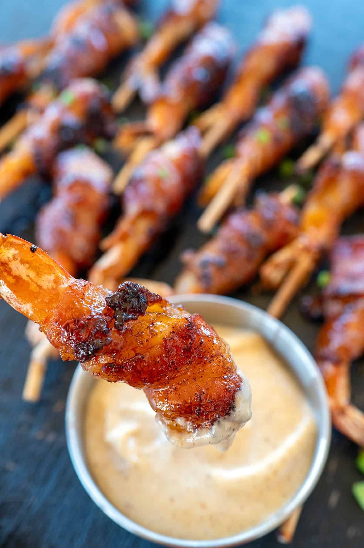 Dipping bacon-wrapped shrimp in aioli.