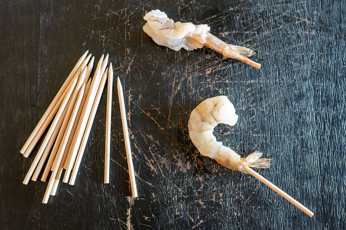 sticking a skewer through shrimp tail.