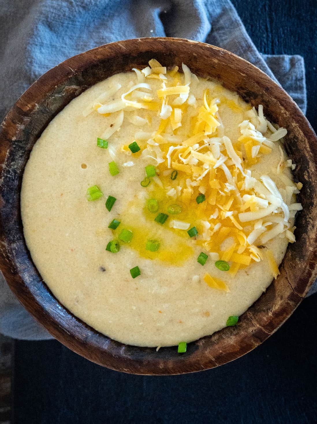 Bowl of cheese grits topped with shredded cheese and green onions.