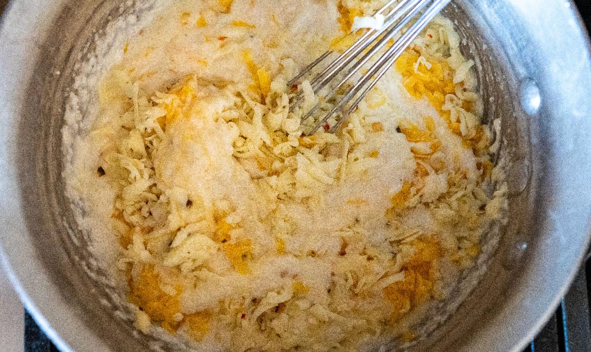 Whisking shredded cheese into grits.