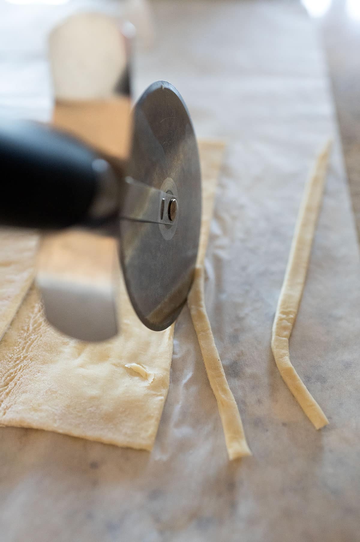 Cutting thin strips of puff pastry with pizza cutter.