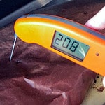 Thermometer showing wrapped brisket at 208F degrees.