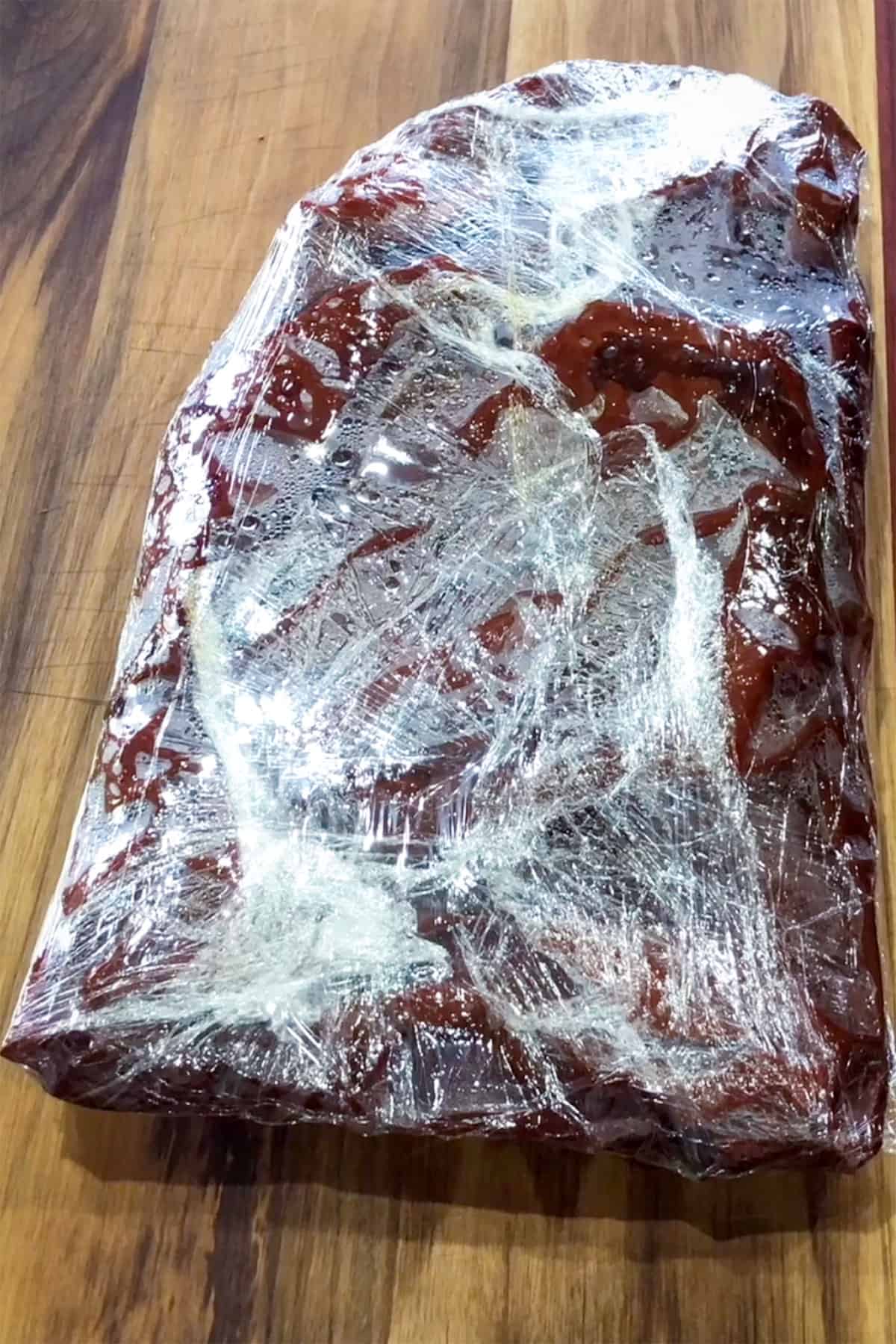 Brisket wrapped in butcher paper and plastic wrap. 