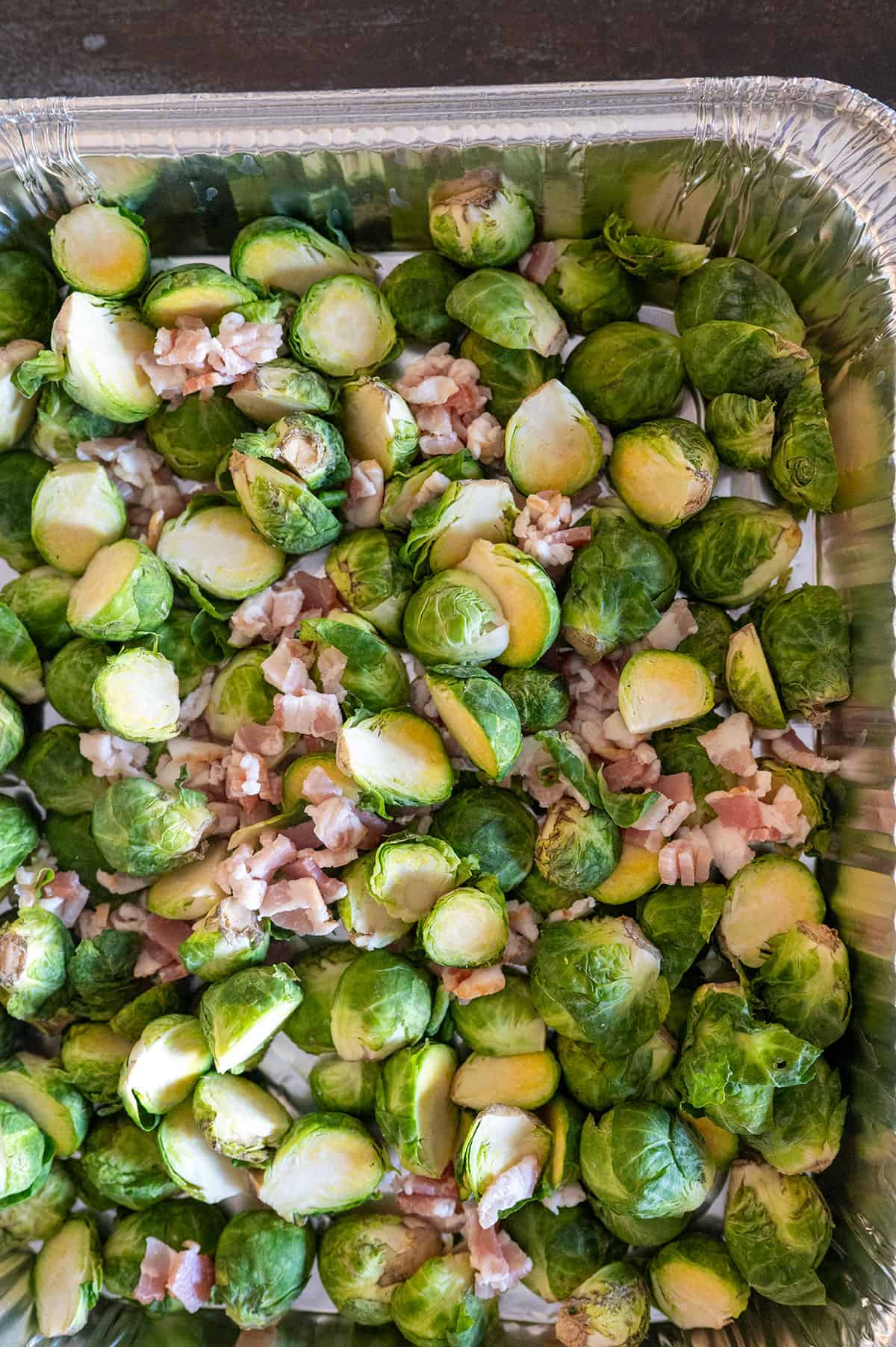 raw brussels sprout halves in pan with bacon.