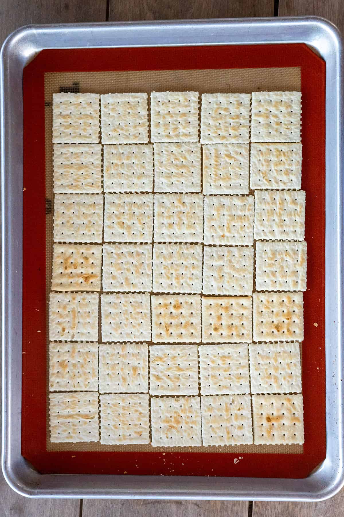 saltines spread out on lined baking sheet.