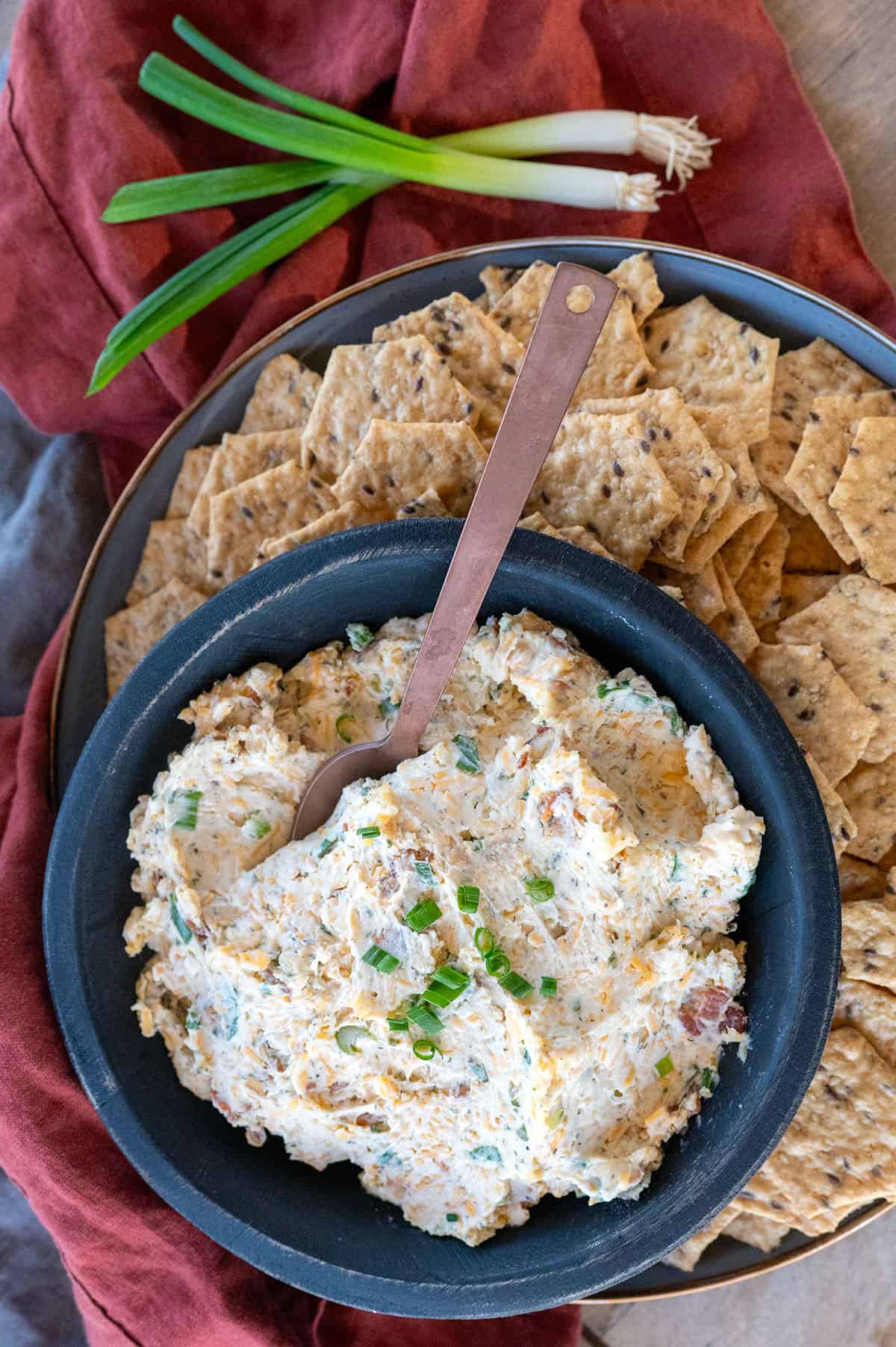 Smoked cream cheese crack dip in black bowl with spoon.