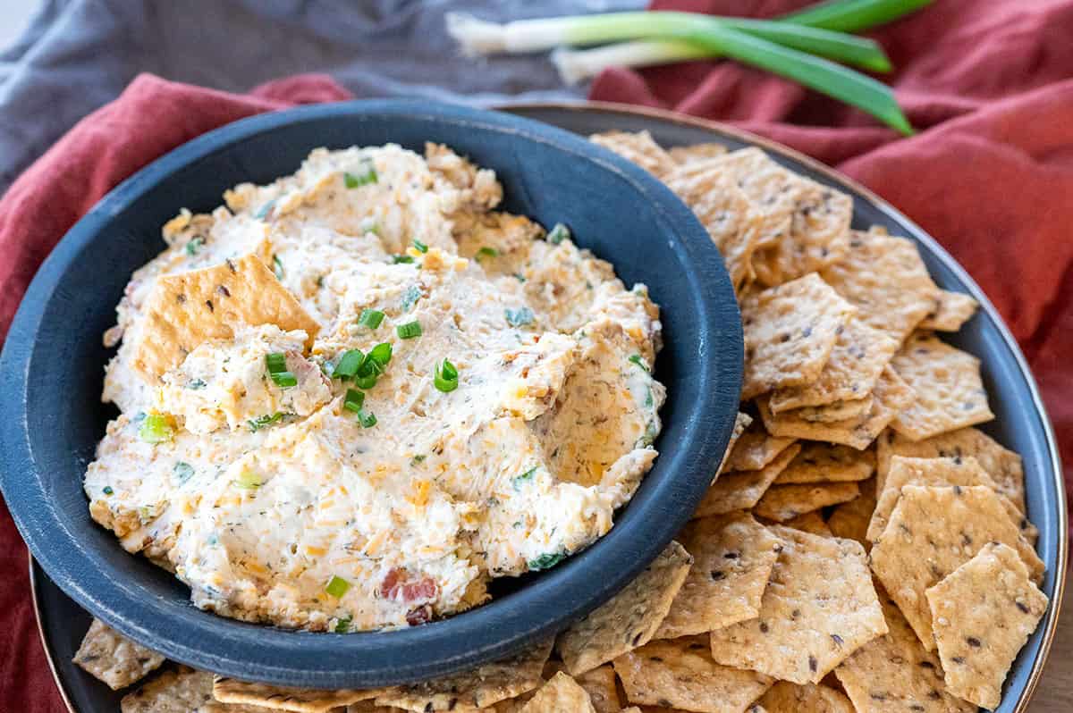 Smoked cream cheese crack dip in black bowl with crackers.