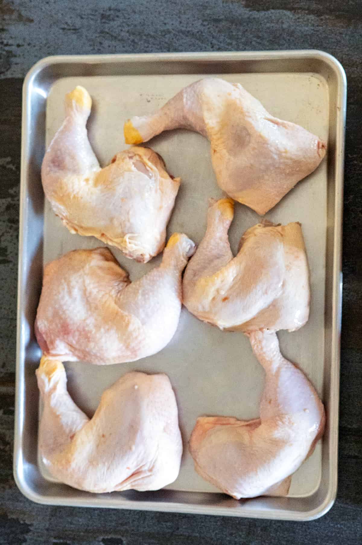 tray of raw chicken quarters.