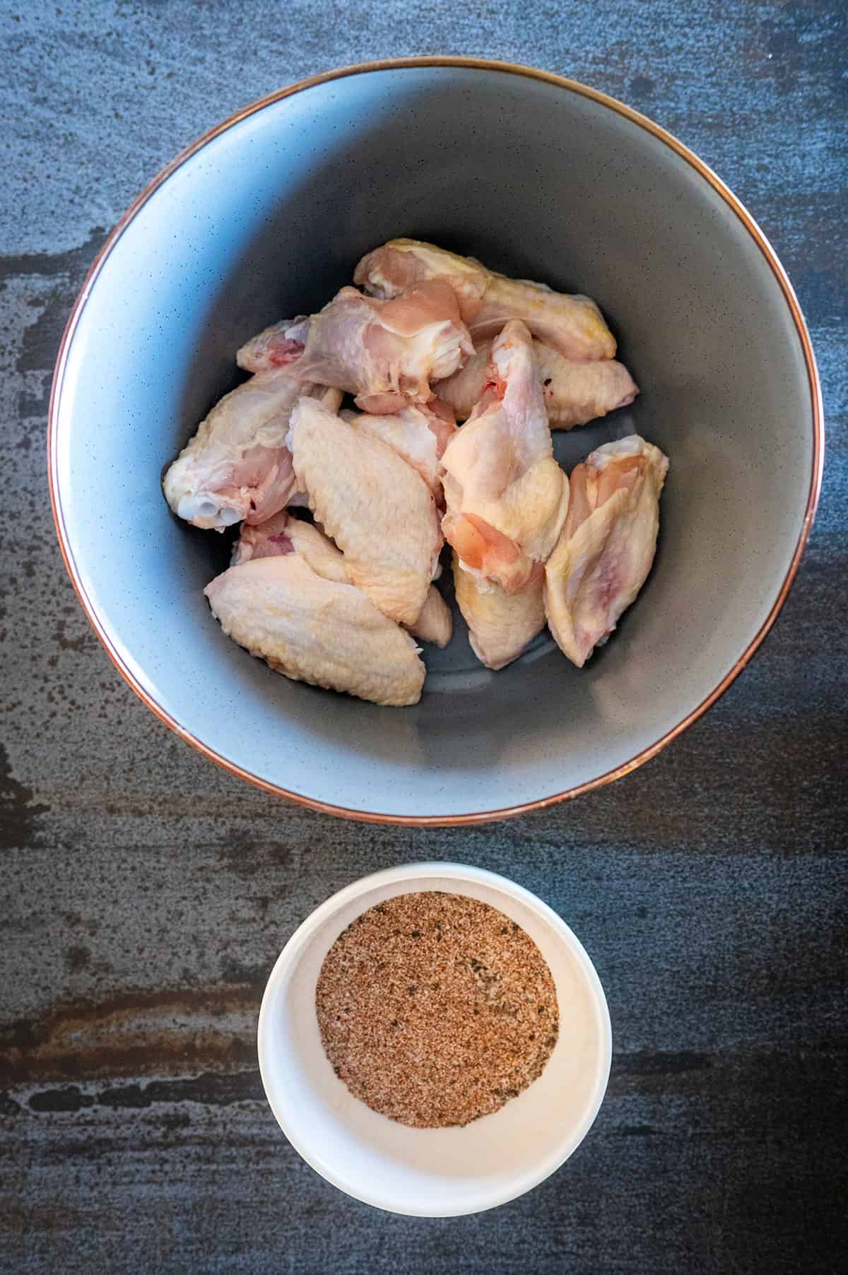 Chicken wings by bowl of dry rub seasoning.