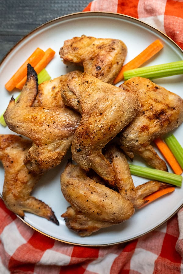 Platter of crispy chicken wings with carrots and celery.