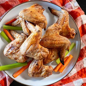 Platter of crispy chicken wings with carrots and celery.