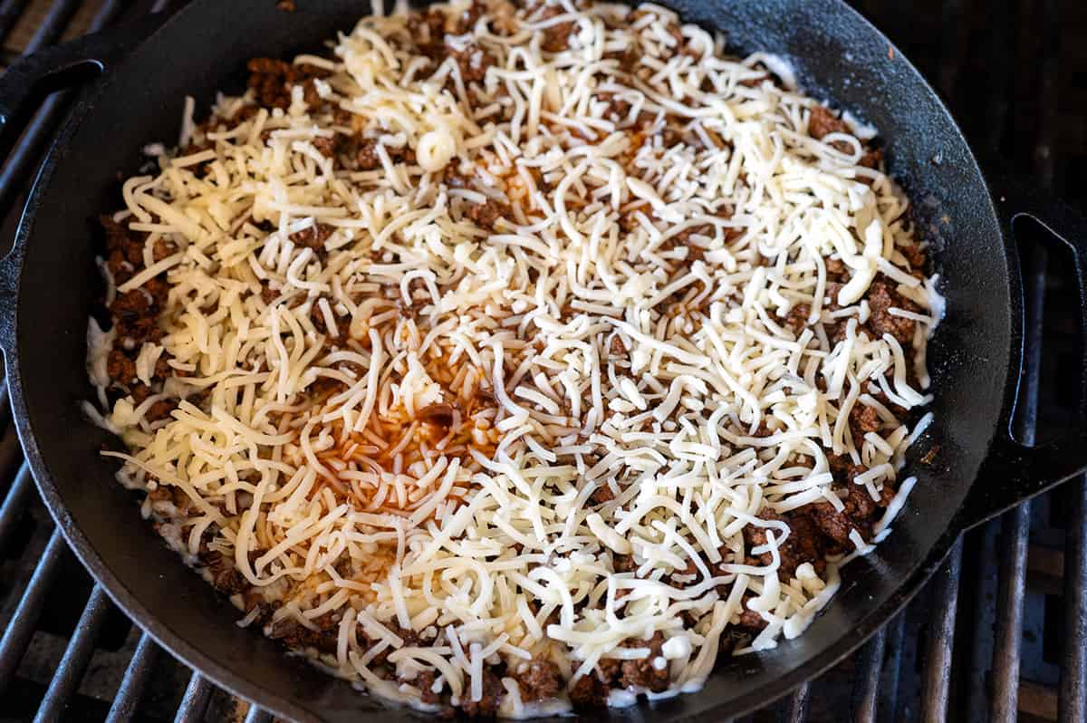 Shredded cheese on skillet of ground meat.