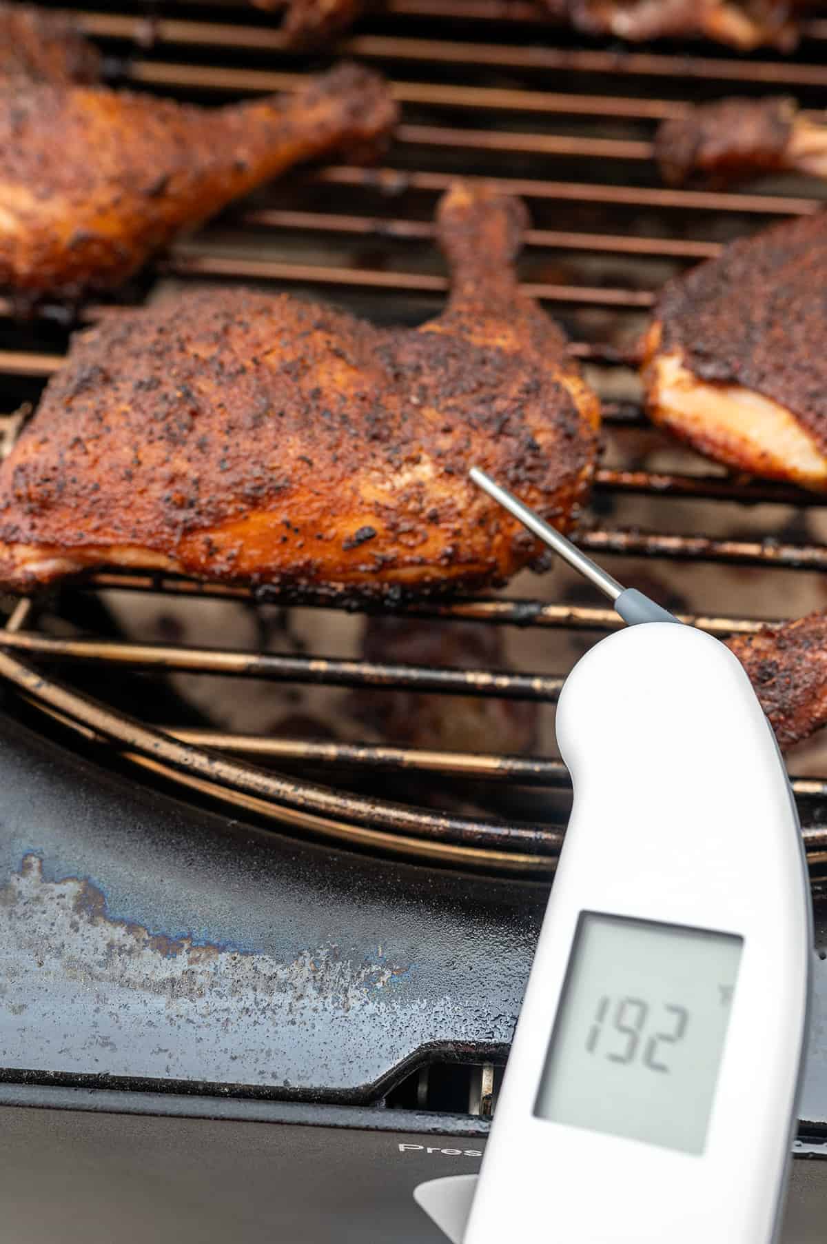 Instant read thermometer showing smoked chicken quarters at 192F degrees.