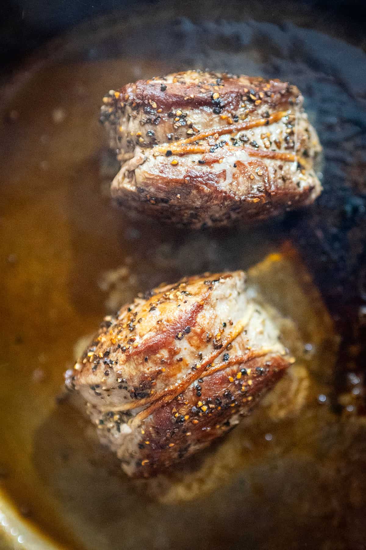 Filet mignon steaks searing on side.