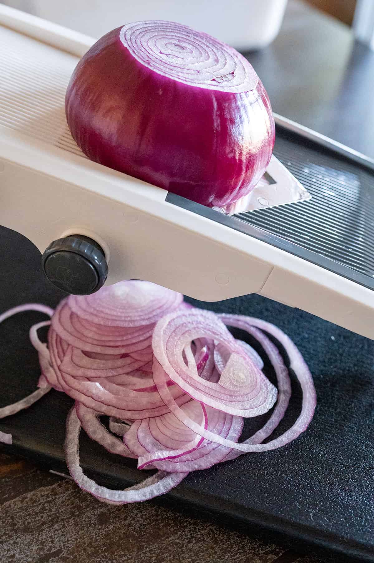 Slicing red onion on a mandoline.