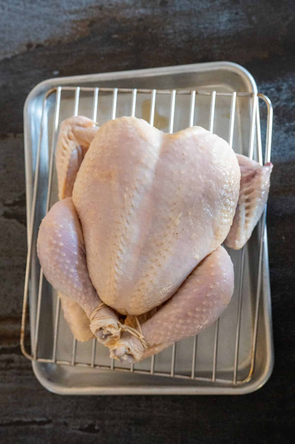 Whole raw chicken on rack.