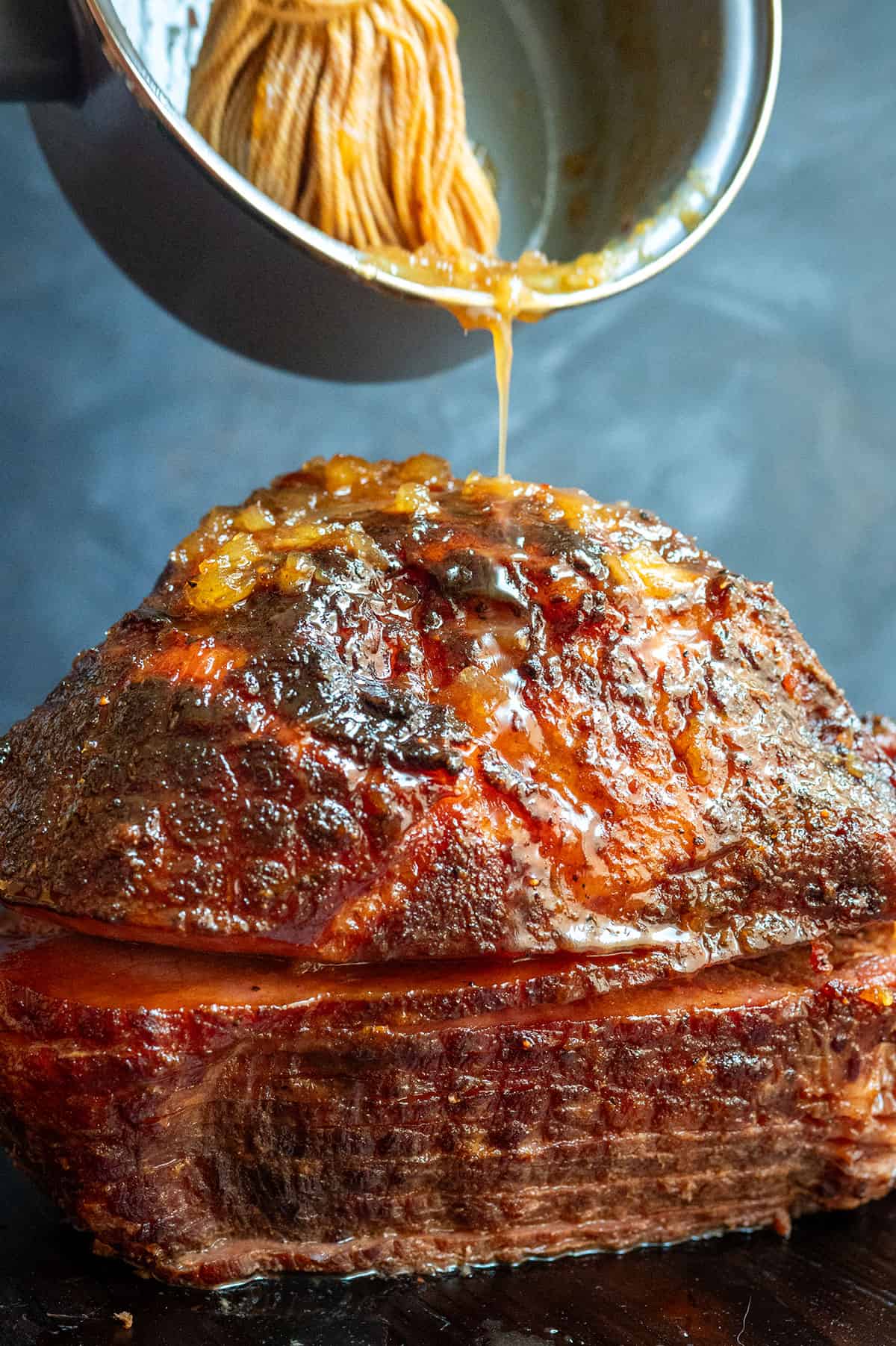pouring ham glaze on ham.