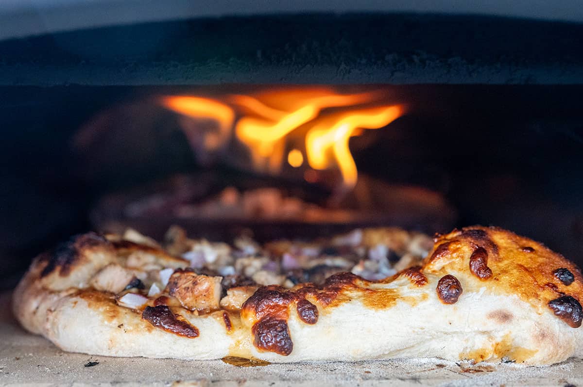BBQ chicken pizza cooking in pizza oven.