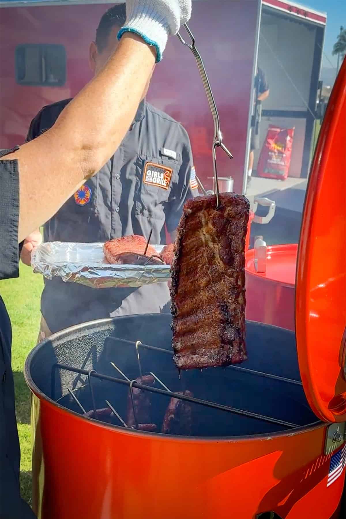 pulling ribs out of drum smoker that have been hanging.