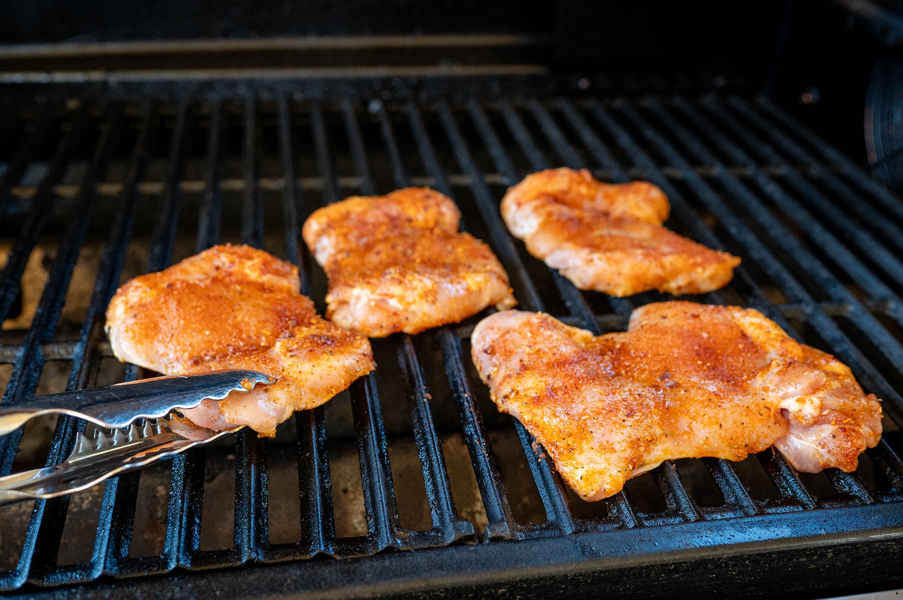 Raw chicken thighs on grill.