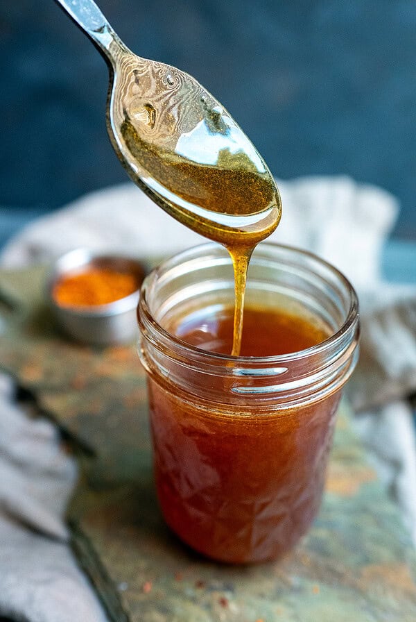 Spoon drizzling gochugaru hot honey.