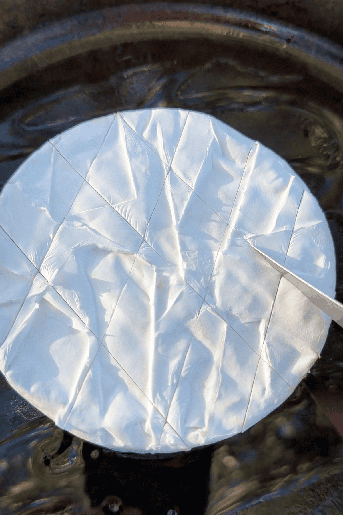Scoring brie with a knife.