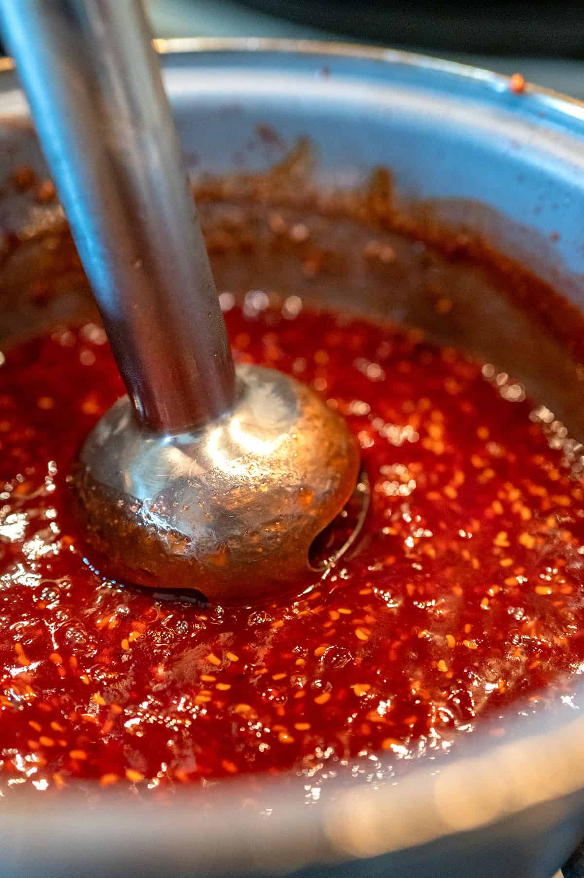 blending Raspberry Chipotle Sauce with an immersion blender.